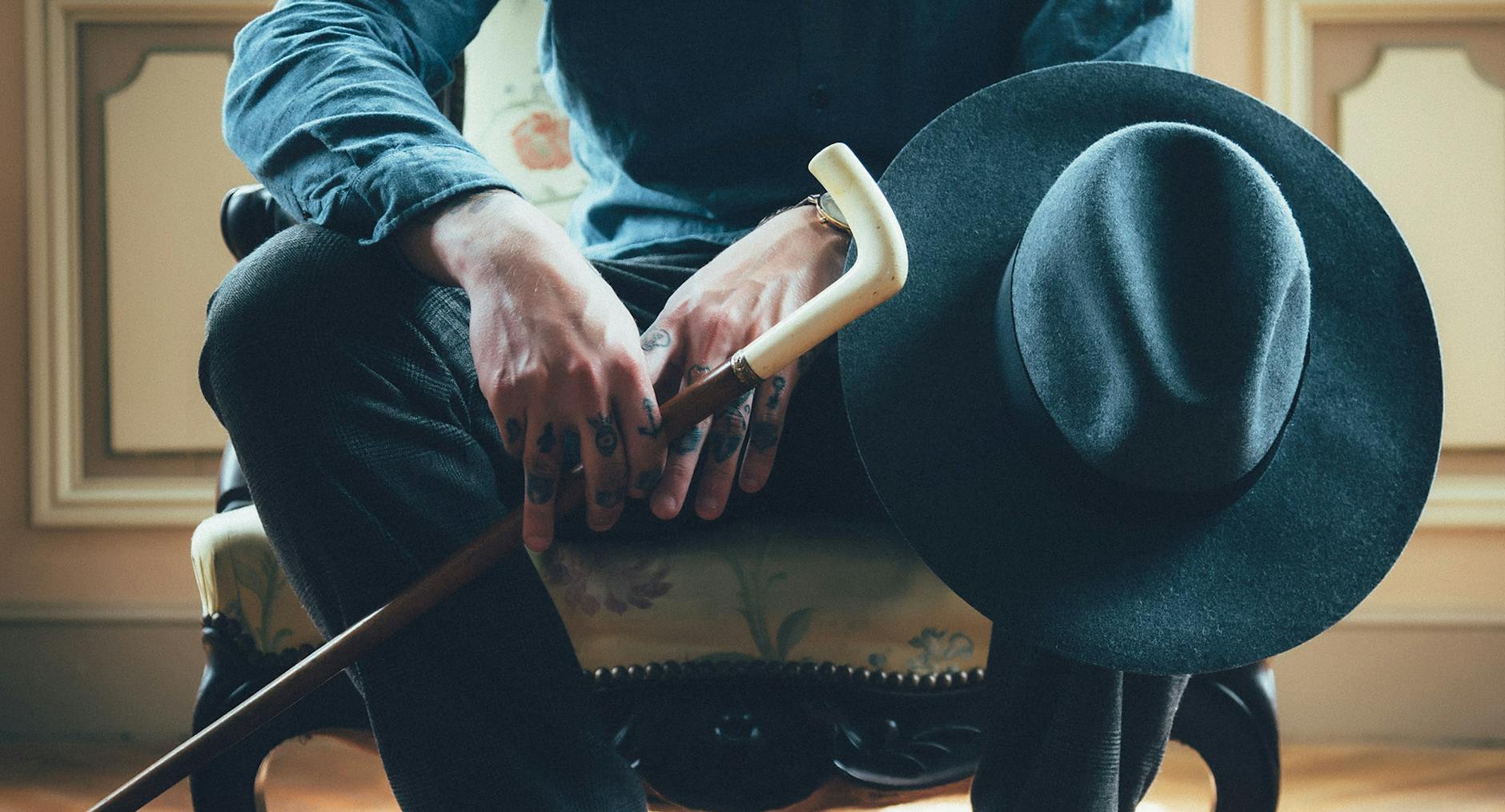 person holding walking cane while sitting on chair